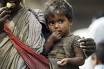 A street beggar carries her child as she begs at a bus station area in Jammu, India, Friday, April 4,