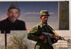 An Afghan military officer stands guard at a checkpoint near a poster of President Hamid Karzai which says "We want peace and national unity in all over of our dear country" in Kabul, Afghanistan, Monday, Nov. 1, 2004. Afghan forces and NATO troops have mounted extra patrols and roadblocks since unidentified armed men on Thursday kidnapped Filipino diplomat Angelito Nayan, and two women - Kosovan Shqipe Habibi and Annetta Flanigan from Northern Ireland. All work for a joint U.N.-Afghan commission overseeing landmark presidential elect