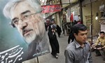 shoppers walk past a defaced poster of leading challenger and reformist candidate Mir Hossein Mousavi, in Tadrish bazaar in northern Tehran. Mousavi is still nominally the guiding force of the fury over Iran's disputed election. But there are ample signs to suggest his rebel stature is being eroded by his hesitation to shift from campaigner to street fighter.