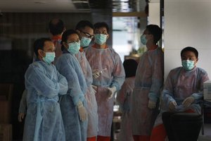 Health officers wearing masks and full body suits stay at the lobby as police seal off Metro Park Hotel in Hong Kong Saturday, May 2, 2009 as the first swine flu victim in the city was confirmed to have stayed there.