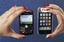 In this photo taken Monday, May 4, 2009, a customer holds up her Apple iPhone, right, which is shown next to a Blackberry Curve, left, at a Best Buy in Mountain View, Calif.