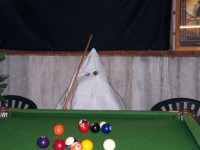 A man in a Klan hood plays pool