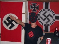 A man salutes in front of Nazi flags