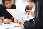 Businesswoman examining graphs with other working people on background