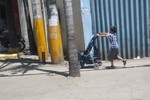 A  child seen pushing a baby stroller  along the sidewalk of EDSA - Quezon City , Philippines, April 12, 2009.