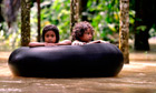 Children float on a rubber ring through flood waters following heavy rains in Thailand