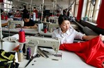 A Chinese woman works at her sewing machine at a garment factory in the suburbs of Beijing, Friday May 20, 2005. China will drastically raise export tariffs on 74 categories of textile products beginning June, the government said Friday, in an apparent effort to meet U.S. and European demands to stem the flood of cheap Chinese