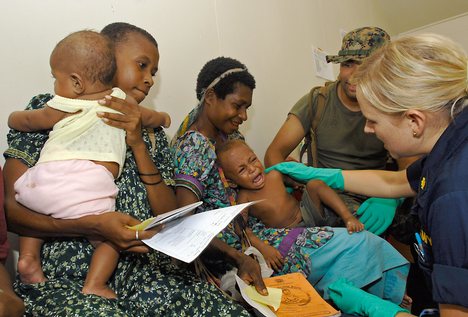 Ensign Stacy Syrstad, a nurse practitioner from Naval Medical Center San Diego, calms a child after a vaccination at a medical civil-assistance program (MEDCAP) at Ileg Clinic near Madang.