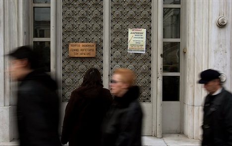 Pedestrians pass outside the headquarters of Greece's General Accounting Office in Athens on Tuesday, Feb. 16, 2010. Employees at the agency joined Greek customs officials in walking off the job Tuesday, for a three-day strike to protest government austerity measures designed to pull the country out of a debt crisis that has shaken the entire eurozone. A poster notifying the public about the strike is taped on the door.Pedestrians pass outside the headquarters of Greece's General Accounting Offi