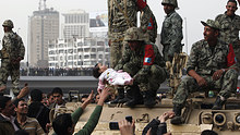 A protester reaches out to a soldier holding a baby on a tank during protests in Cairo.