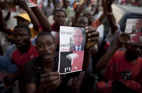 A supporter of Haiti's former dictator Jean-Claude Duvalier holds up an image of Duvalier outside the rented guest house where Duvalier is staying in Port-au-Prince, Haiti, Friday Jan. 21, 2011. Duvalier  returned Sunday to Haiti after nearly 25 years in exile, a move that comes as his country struggles with a political crisis and the stalled effort to recover from last year's devastating earthquake. Duvalier  said Friday it was the earthquake that brought him back to Haiti and that he wants to help with the reconstruction.