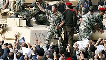 An Egyptian Army soldier standing atop a tank in Cairo gestures to a crowd of demonstrators