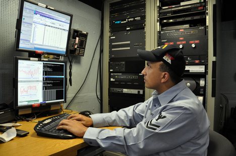 U.S. Navy Information Systems Technician 2nd Class James Rago troubleshoots the video teleconference system of a video information exchange system.