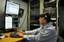 U.S. Navy Information Systems Technician 2nd Class James Rago troubleshoots the video teleconference system of a video information exchange system.