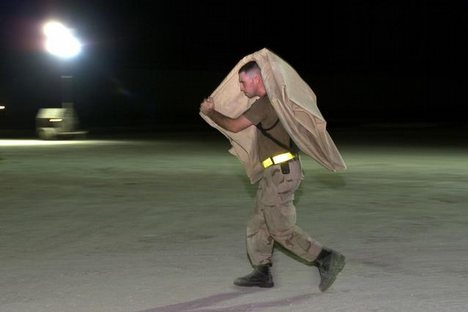 A lone airman carries part of a TEMPER (Tent, Extendable, Modular, Personnel) tent section to its construction location, soon to be part of the new dining facility tent, while deployed at an undisclosed location in support of Operation ENDURING FREEDOM. I