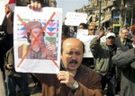 Protesters demonstrate against Libyan Leader Moammar Gadhafi, shown on placard at left, in the Mediterranean port city of Alexandria in Egypt Sunday, Feb. 20, 2011. Libyan forces fired machine-guns at mourners marching in a funeral for anti-government protesters in the eastern city of Benghazi Sunday, a day after commandos and foreign mercenaries loyal to longtime leader Moammar Gadhafi pummeled demonstrators with assault rifles and other heavy weaponry. Writing in Arabic on placard reads "Down, the leader of the Abu Salim massacre", referring to an incident when hundreds of inmates were killed when security forces opened fire during 1996 riots at Libya's most notorious prison.