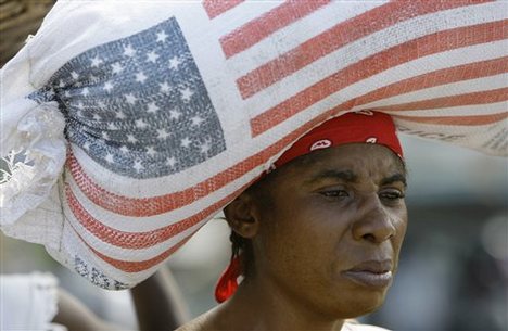 A woman carries a bag containing rice donated by the United States Agency for International Development, USAID, as she walks through a market in Leogane, Haiti Saturday, Jan. 16, 2010. A powerful earthquake hit Haiti on Tuesday.