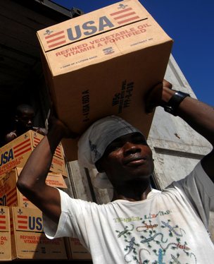 Haitian workers move cooking oil supplied by the United Stated Agency for International Development (USAID) at a distribution center at Port-Au-Prince international airport.