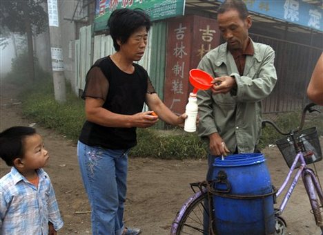 A Chinese child looks up as a woman purchases fresh milk from a cow farmer near Zhengting, northern China's Hebei province, Saturday, Sept. 20, 2008.