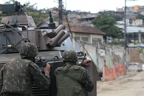 Soldiers take position behind an armored vehicle during an operation against drug traffickers at the Complexo do Alemao slum in Rio de Janeiro, Brazil, Saturday, Nov. 27, 2010. Occasional gunfire broke the tense stillness Saturday morning as armored vehicles prepared to push past barriers into Rio's most dangerous slum, as police increased pressure on drug traffickers believed to have ordered the wave of violence that has terrorized the city this week.