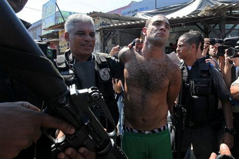 An alleged drug trafficker known as Zeu, center, is arrested during a police operation at the Complexo do Alemao slum in Rio de Janeiro, Brazil, Sunday, Nov. 28, 2010. Rio's most dangerous slum that was the backbone of the city's biggest drug gang was taken by 2,600 police and soldiers Sunday, an unprecedented accomplishment by authorities in their fight to secure this seaside metropolis that will host the 2016 Olympics.