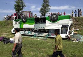 Rescuers pass by an overturned bus beside a highway in Xinmin City, northeast China´s Liaoning Province, Aug. 23, 2003. The accident occurred when a bus collided with a minivan on the highway early Saturday, leaving one people dead and 12 others inj