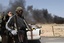 Smoke billows as Libyan rebels are seen some 120 km (75 miles) east of Sirte in eastern Libya,Monday, March 28, 2011. Rebel forces on Monday fought their way to the doorstep of Moammar Gadhafi's hometown of Sirte, a key government stronghold guarding the road to the capital Tripoli.