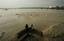 Locals smoke tobacco on a section of a bridge amidst rising flood waters of the River Yamuna in New Delhi, India, Friday, Sept. 10, 2010.