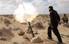 A Libyan rebel shells pro Gadhafi forces with mortar fire, along the front line outside the eastern town of Brega, Libya Thursday, March 31, 2011.