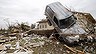 A vehicle rests on a tree after an overnight tornado in Tushka, Okla., Friday, April 15, 2011. (AP Photo/Sue Ogrocki)