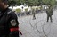 A police officer wearing a red armband stands next to soldiers as he demonstrates in Tunis, Saturday, Jan. 22, 2011. Tunisia's  once-feared police who carried out the repressive policies of their now exiled president are joining hands with protesters who brought down the dictator. Clusters of police guarding the daily protests on the capital's main avenue are mingling with the crowd.