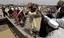 People walk over a makeshift bridge set-up over the damaged portion of a main highway in flood hit area Charsadda, Pakistan on Saturday, July 31, 2010.