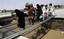 People walk over a makeshift bridge set-up over the damaged portion of a main highway in flood-hit area Charsadda, Pakistan on Saturday, July 31, 2010.