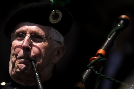 A bagpiper plays the Navy Hymn during a dedication ceremony for the Arleigh Burke-class guided-missile destroyer, USS Michael Murphy (DDG 112).