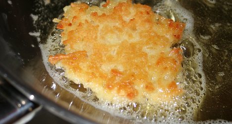 A latke or potato pancake made with egg frying in oil.