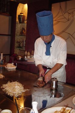 A teppanyaki chef cooking at a gas powered teppan in a Japanese steakhouse.(在气动力在日本牛排屋铁板烧铁板烧厨师烹饪。)