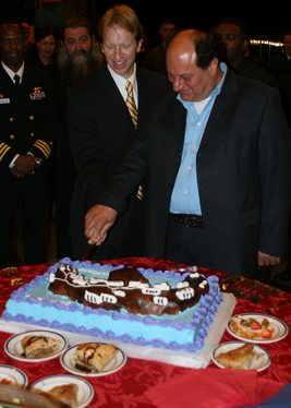 U.S. Ambassador to Greece Daniel Speckhard, left, and Santorini, Greece Mayor Angelos Roussos cut a ceremonial cake during a reception aboard the amphibious transport dock ship USS San Antonio (LPD 17).