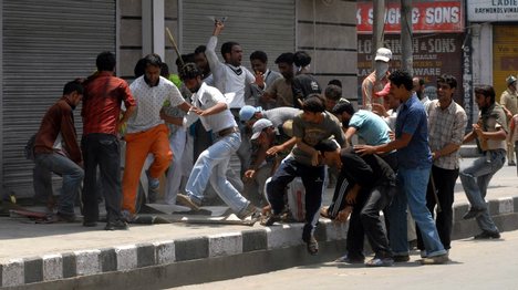 An Indian Kashmiri protestor climbs up a wall to tear down a billboard of a pro-India party during a demonstration in Srinagar on June 27, 2008.