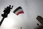 An anti-government protester waves an Egyptian flag as stands on a pole in Tahrir Square, Cairo, Egypt, Friday, Feb. 4, 2011.