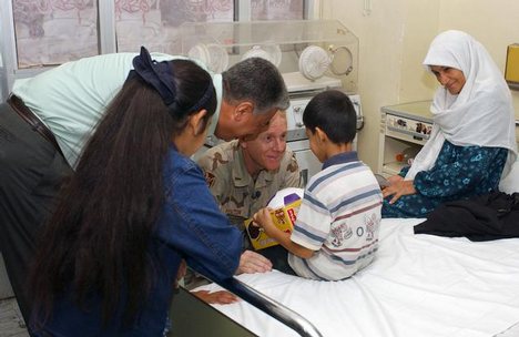 US Army (USA) Chief Warrant Officer (CWO) Paul Holton, with the 141st Military Intelligence Battalion (MIB), Utah Army National Guard (ANG) chats with a sick Iraqi child after giving him a soccer ball at the Baghdad Children's Hospital, Baghdad, Iraq (IRQ