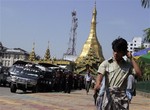 Pedestrians walk past riot police trucks stationed outside the City Hall Thursday, Nov. 4, 2010, in downtown Yangon, Myanmar. The military government has tightened security in Yangon as the Nov. 7 elections draws near.