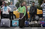 File - Romanian Roma women look at journalists after they and more than 200 others arrived on two special flights from France, in Bucharest, Romania, Tuesday, Sept. 14, 2010.