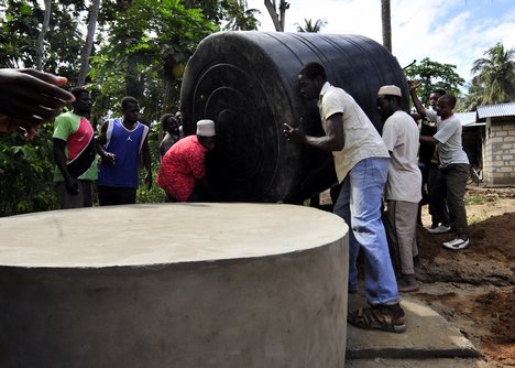 Residents of Fundo Island, a small islet that is part of Pemba Island, carry a 5,000-liter water cistern to a concrete support pad.