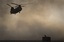 A US Marine tries to take cover, perched on a container, trying to shelter from the dust as a Chinook helicopter arrives to pick up supplies at Forward Operating Base Edi in the Helmand Province of southern Afghanistan, in this June 9, 2011 file photo.