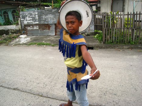 An ati-atihan drummer boy hands over an envelope for some donation.