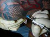 A tattoo artist performs a tattoo.()