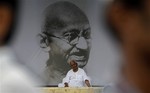 Anti-corruption activist Anna Hazare sits in front of a giant portrait of Mahatma Gandhi, on the 9th day of his hunger strike in New Delhi, India, Wednesday, Aug. 24, 2011.