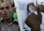 In this photo taken on a government-organized tour, showing a Libyan man holding a Moammar Gadhafi's portrait as he and others rally at the Green Square in central Tripoli, Libya, on Friday, June 24, 2011.