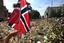 A woman touches a Norwegian flag as people gather around thousands of flowers and tributes laid outside the Oslo Cathedral in Oslo, in memory of the victims of July 22 bomb attack and shooting rampage, Monday, Aug. 1, 2011