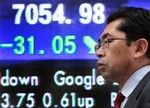 A man walks in front of the electronic stock board of a securities firm in Tokyo, Japan, Tuesday, March 10, 2009. Japanese stocks continued their slide Tuesday as ongoing concerns about the global economy dragged the benchmark Nikkei index to a fresh 26-year closing low.